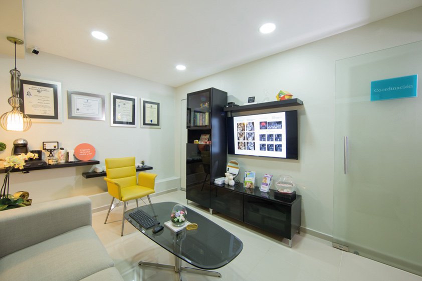 Oficina con sillón amarillo y mesa de vidrio